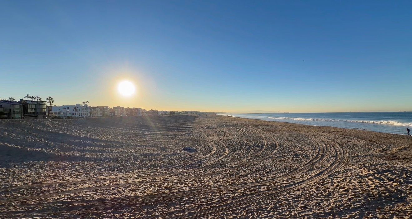 Panoramic view of a freshly plowed agricultural field under bright blue sky at sunset.