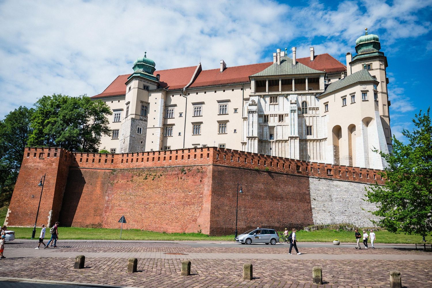 Historic Wawel Royal Castle with red brick fortification walls rises majestically against blue sky in Krakow, Poland.