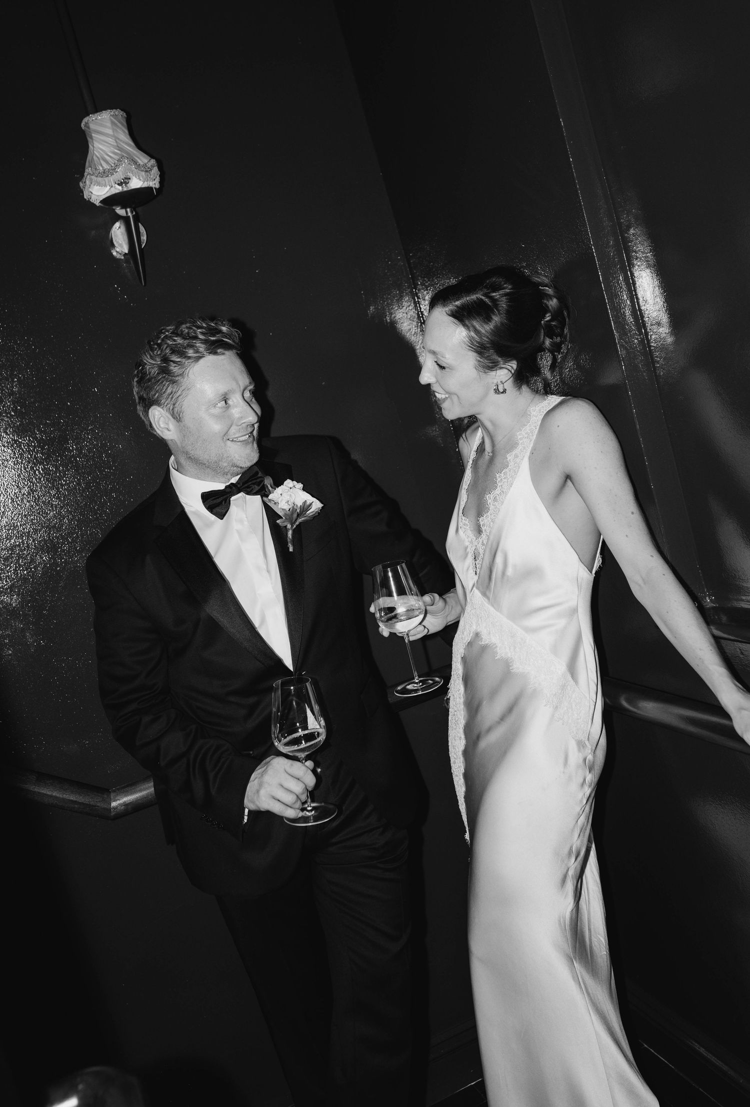 A couple in formal attire sharing drinks at an elegant black-tie event.
