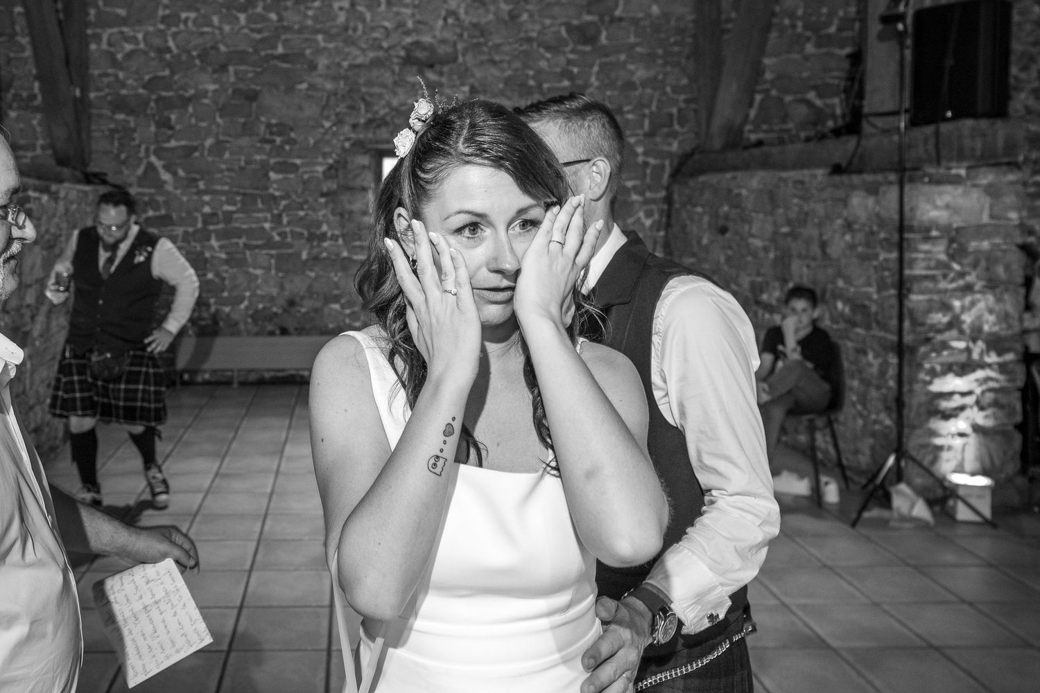 Black and white photo of a candid reaction from wedding guests during a memorable reception moment.