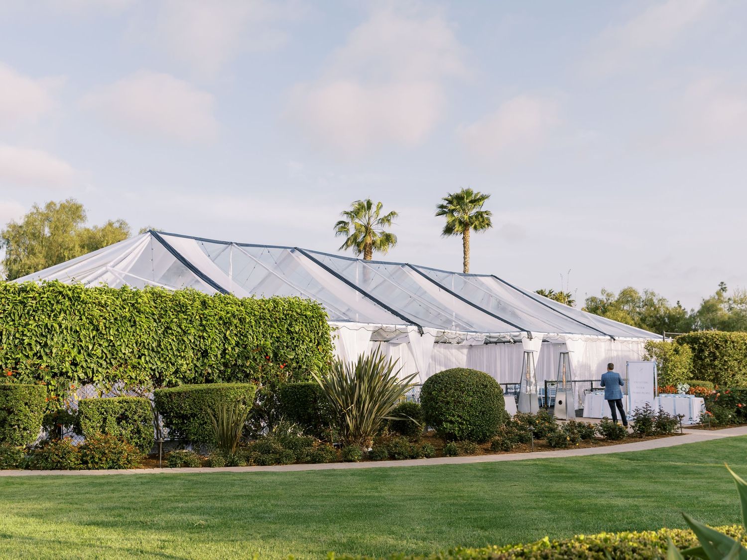 White church building with Spanish colonial architecture and palm trees against a bright blue sky in Newport Beach.