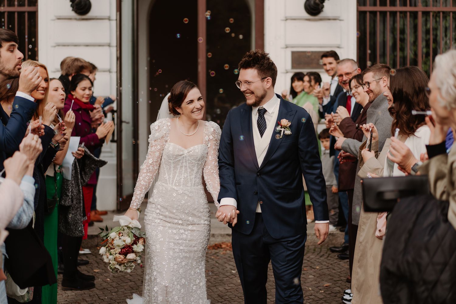 A romantic wedding couple embraces in sunlit garden setting at golden hour.