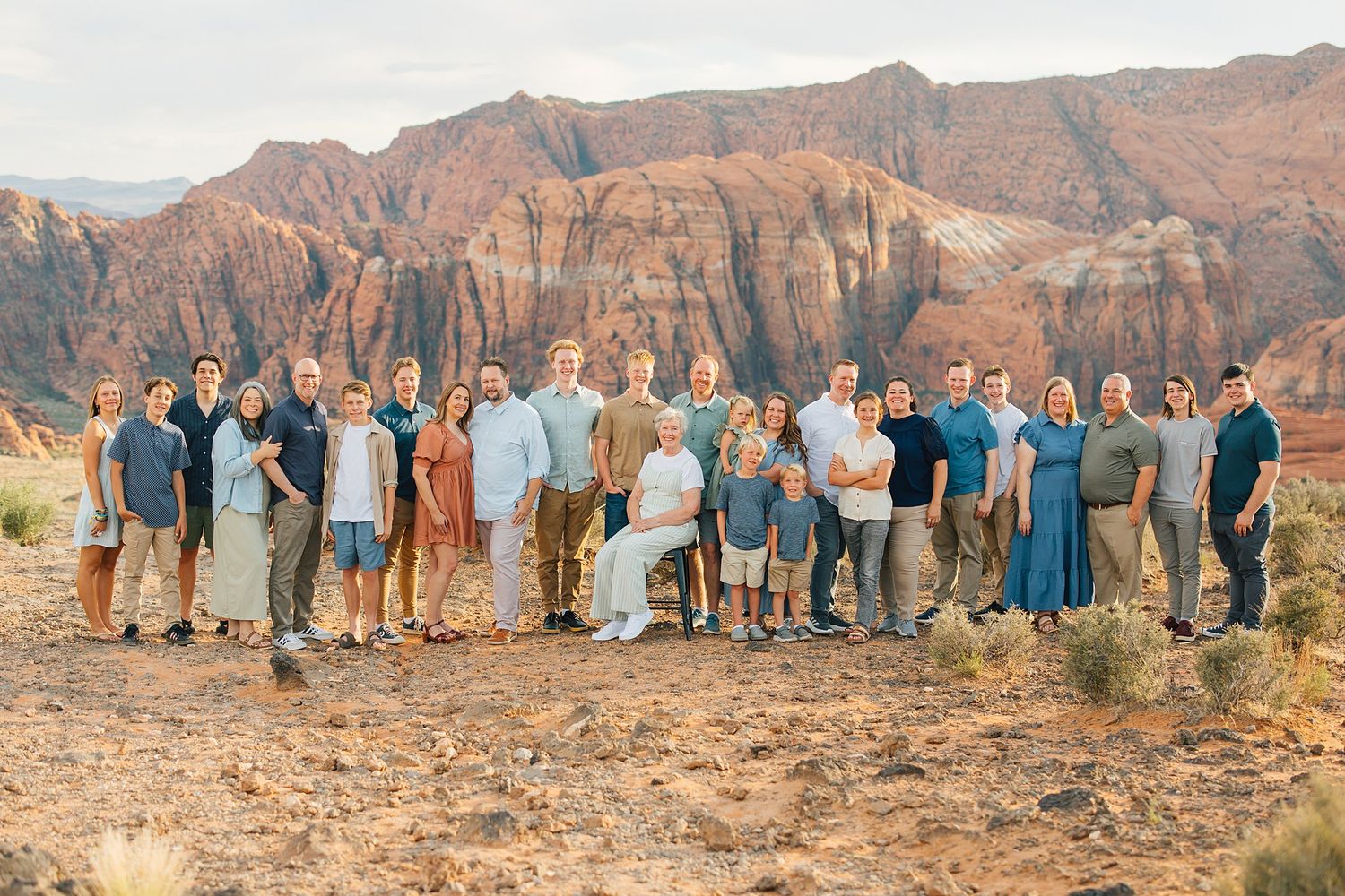 Large group gathered for photos with towering red rock formations in the desert landscape.