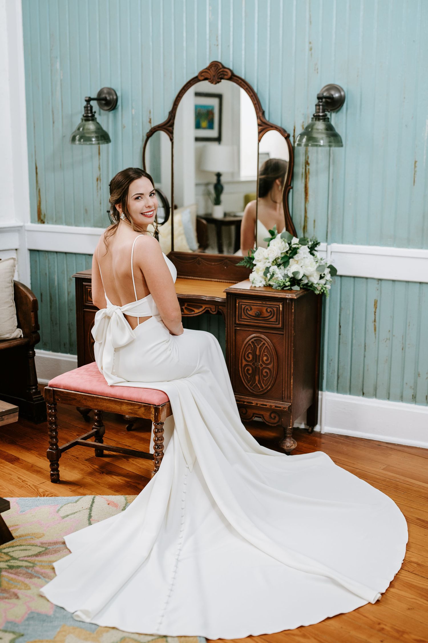 A bride in a flowing white wedding dress twirls and spins in a rustic blue room with wooden furniture.