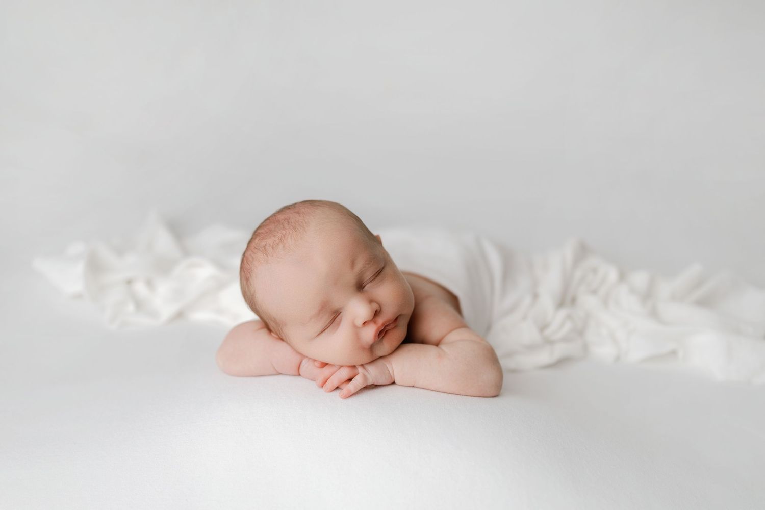 posed newborn photography image with baby posed on white neutral fabric in Magnolia, TX studio