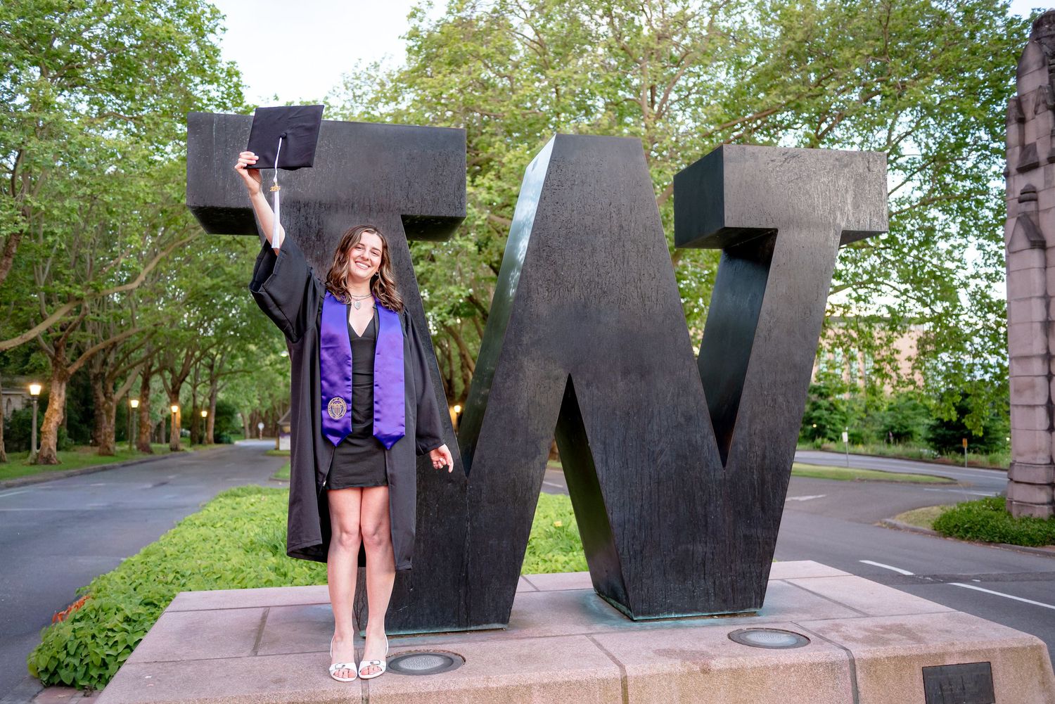 University of Washington graduate celebrating beside the W Sculpture during a graduation photo session in Seattle