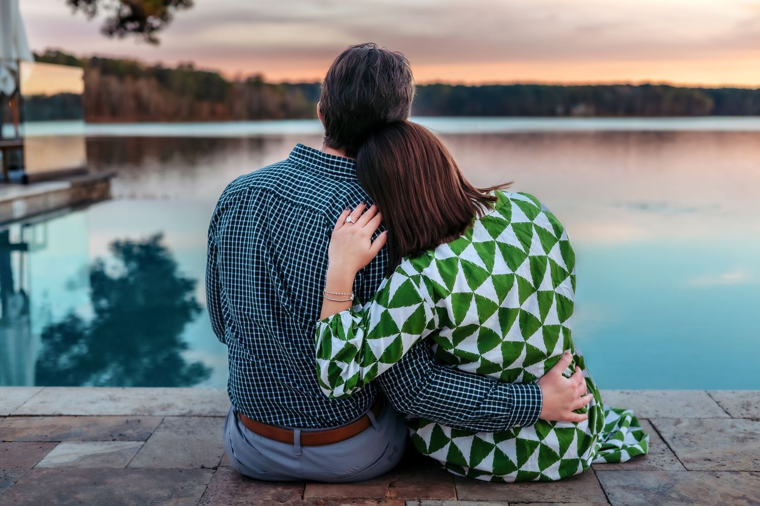 Couple sitting on dock at sunset after surprise proposal at Ritz-Carlton Reynolds Lake Oconee photographed by Athens Georgia photographer