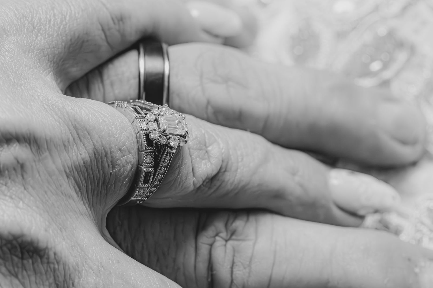 Close-up black and white photo of two hands wearing wedding rings, symbolizing marriage and commitment. wedding photographer