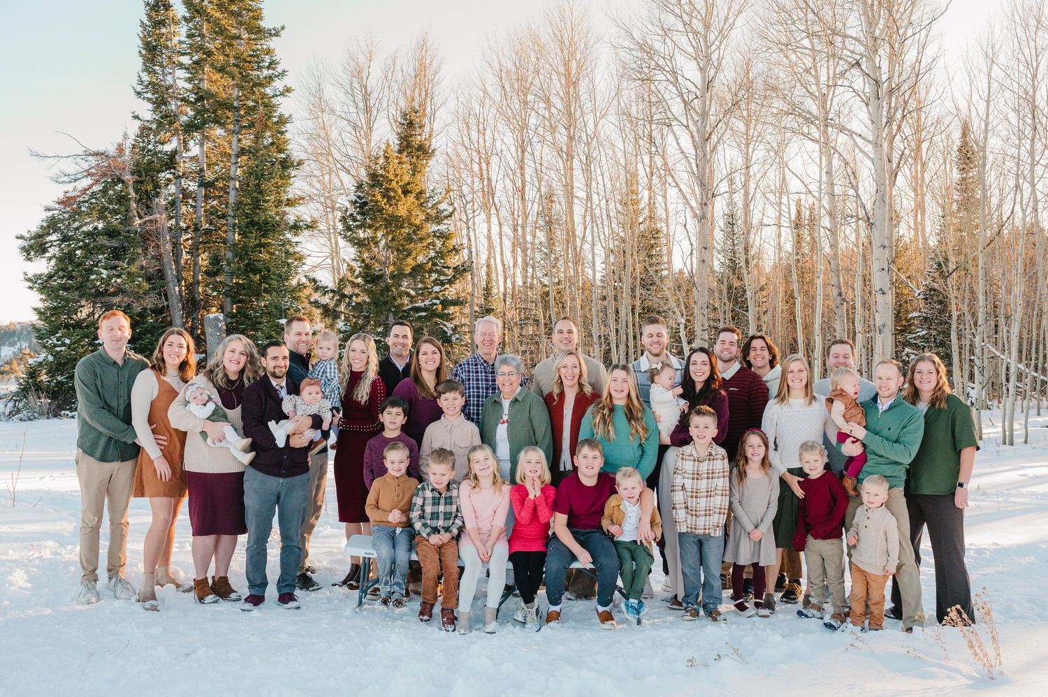 A group of people standing together in a snowy winter landscape with evergreen trees and birch trees in the background.