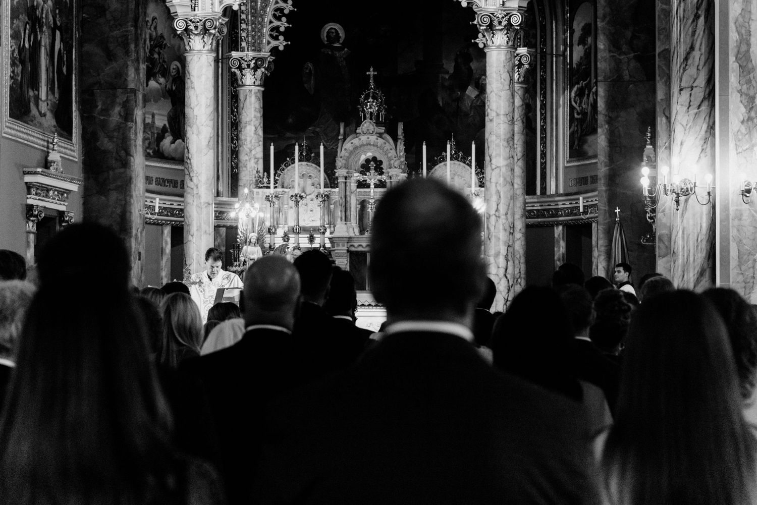 Black and white photo of wedding guests gathered in an ornate church during a ceremony.