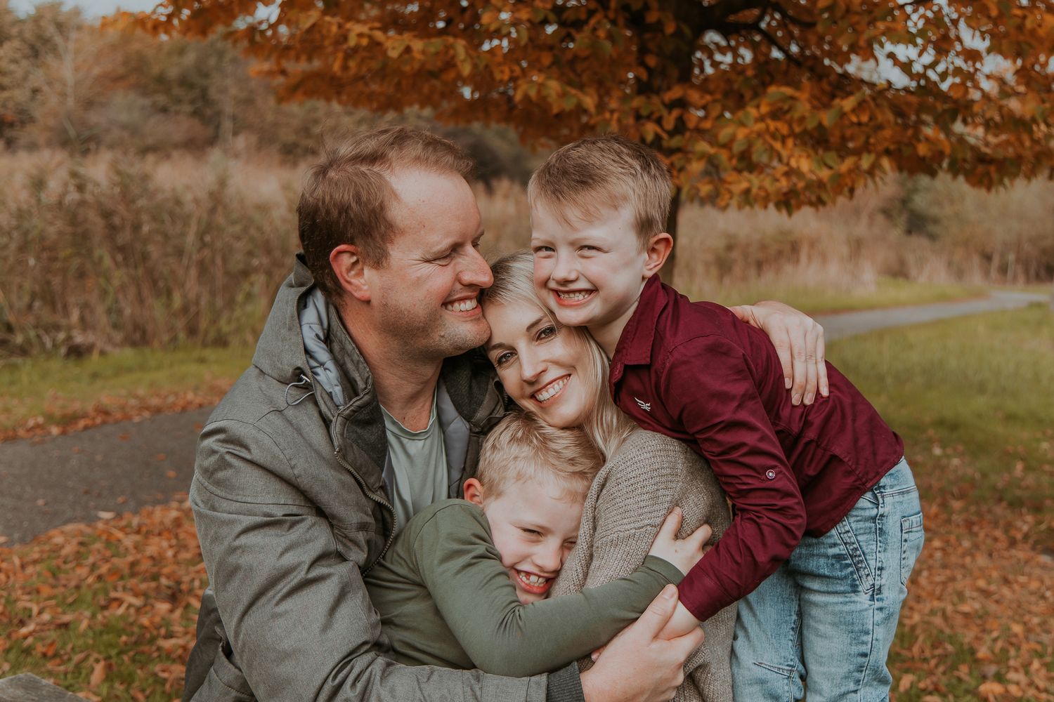 Family during an autumn photoshoot at Maximapark in Utrecht, walking among the colorful trees and fallen leaves.