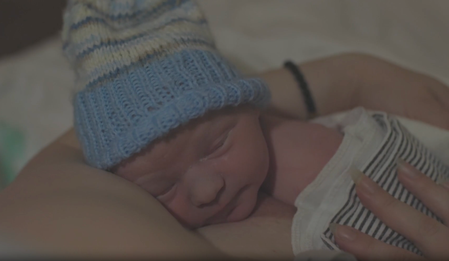 Newborn baby Indy sleeping on his mother's chest, wearing a blue hat, after his waterbirth at the Ottawa Birth and Wellness Centre.