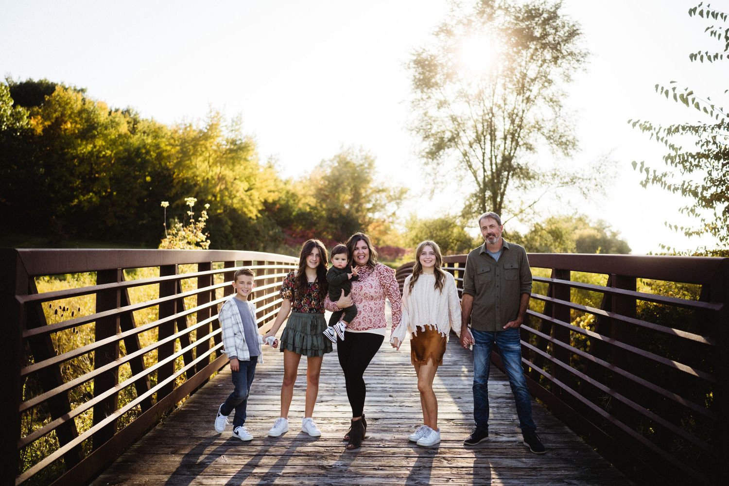 Group walking together on a wooden bridge during golden hour sunset.