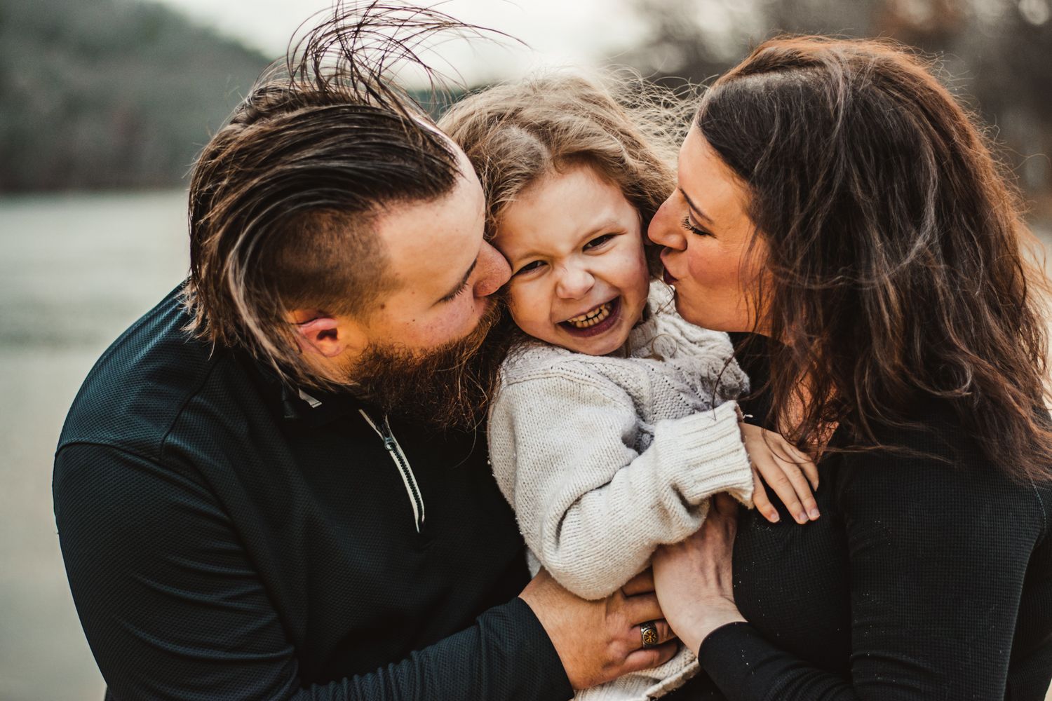 An intimate family moment captured outdoors against a moody natural backdrop.