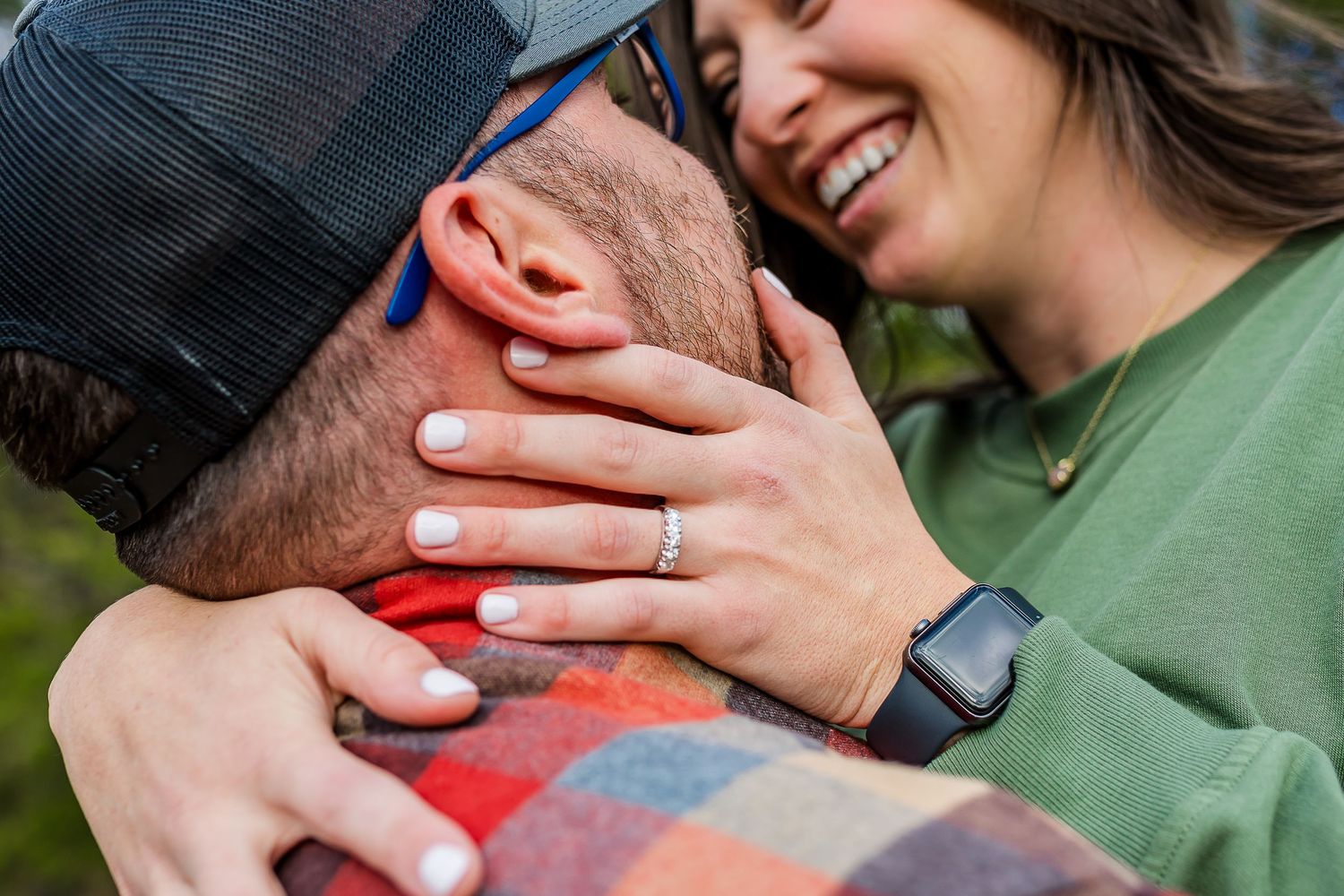 Close up of engagement ring as couple shares tender moment outdoors.