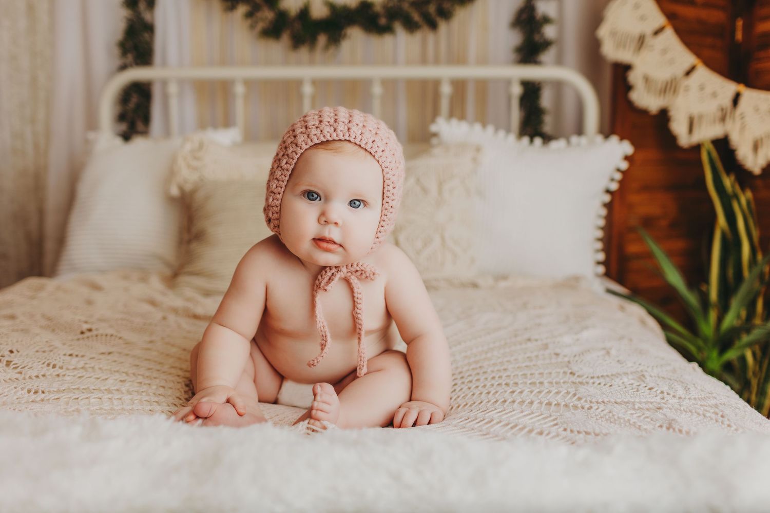 Baby portrait session on cream blanket with holiday wreath decor in background.
