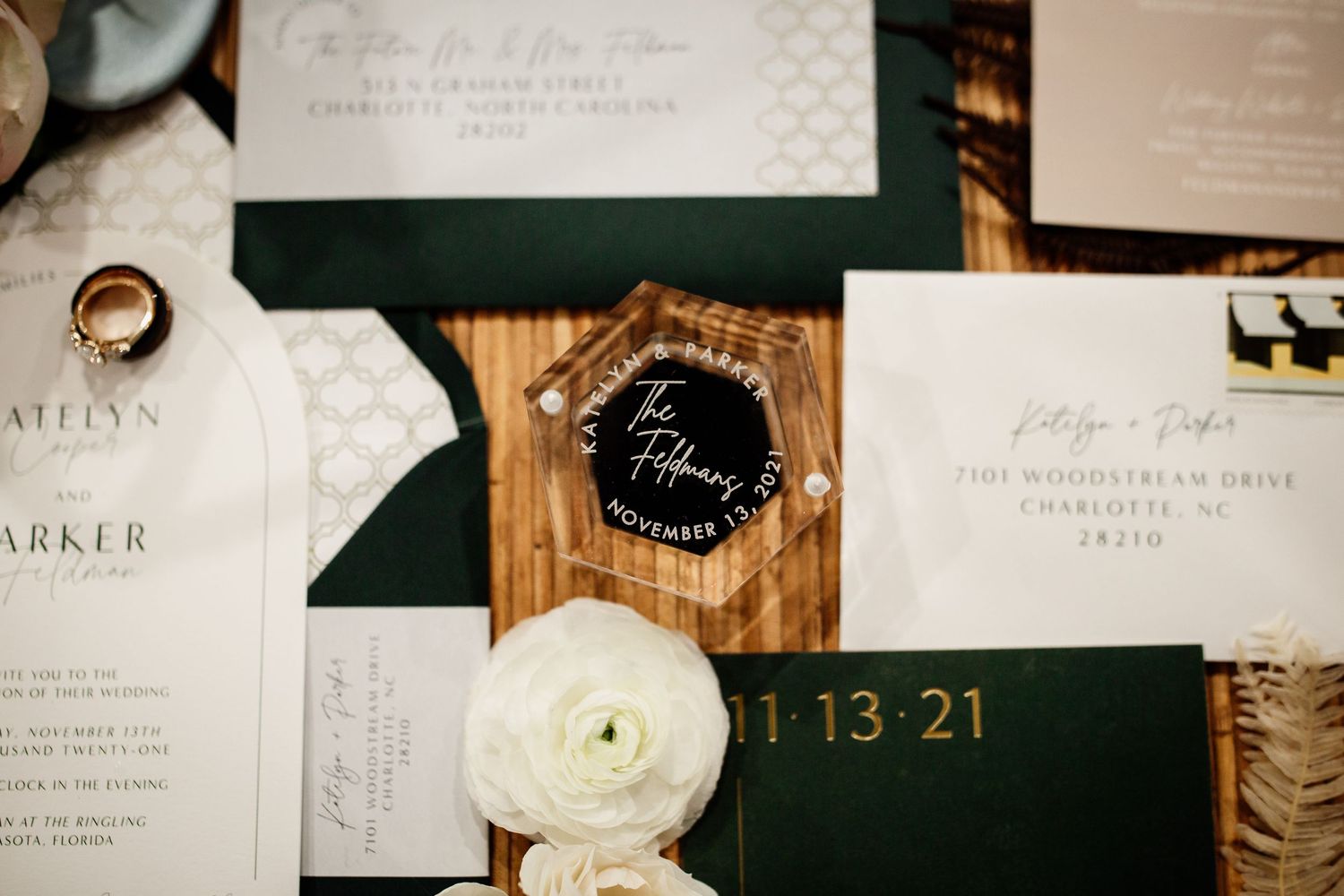 White and green wedding stationary focusing on a clear acrylic ring box.
