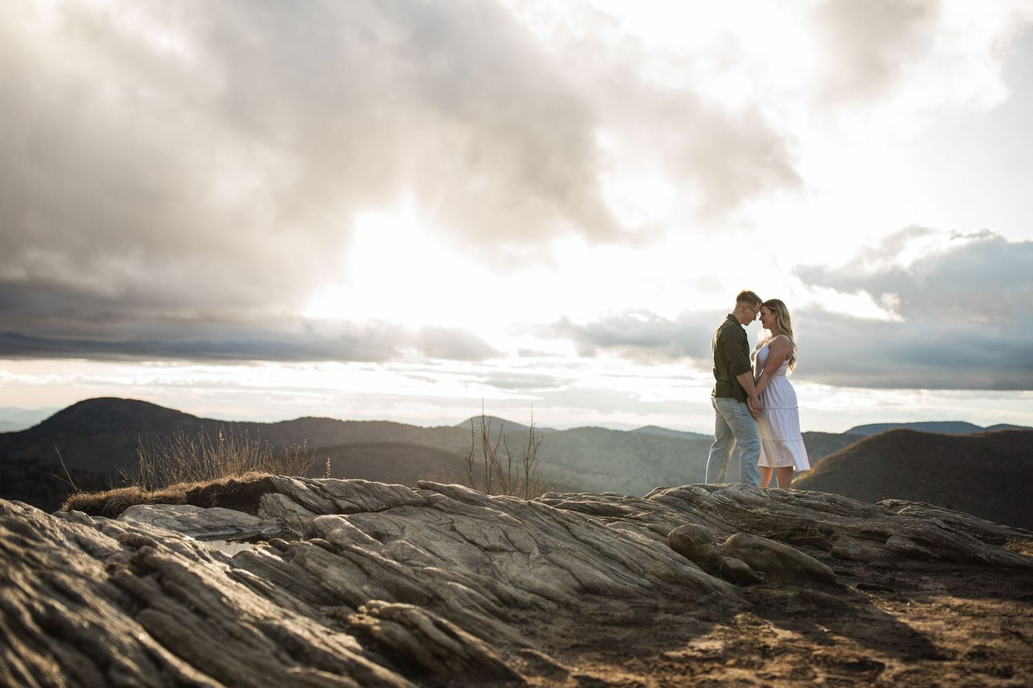 A romantic wedding photo on a dramatic mountain peak at sunset.