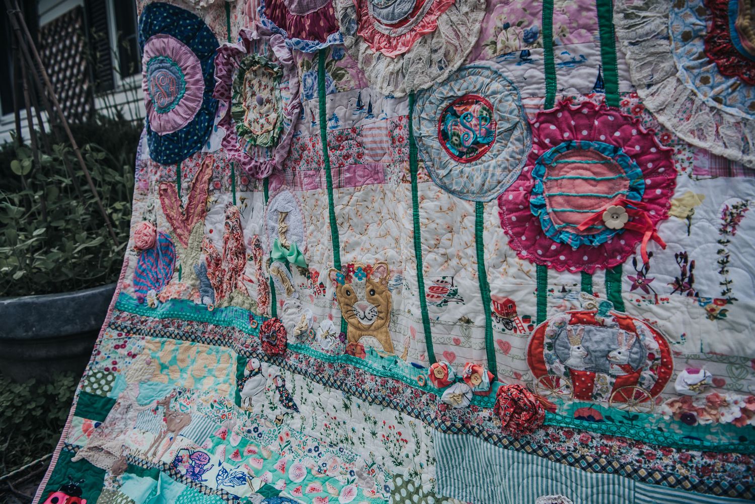 Colourful memory quilt with lots of flowers and animal appliques made from baby clothes.