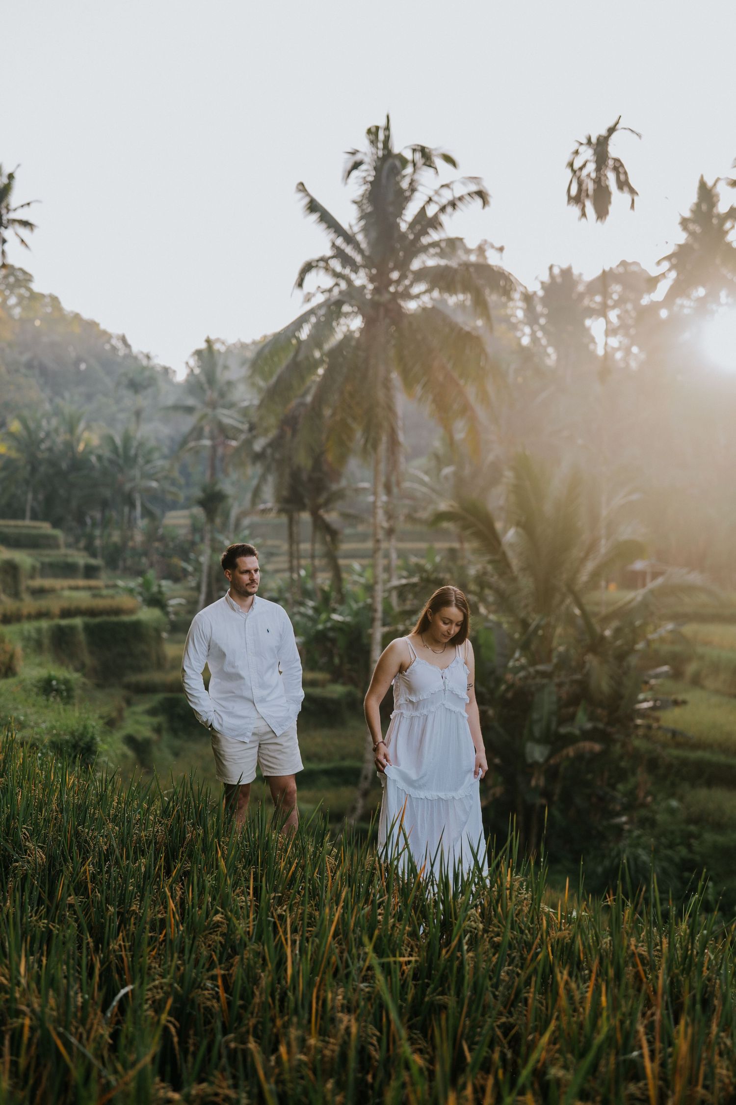 A couple poses on a rope bridge surrounded by tropical vegetation.