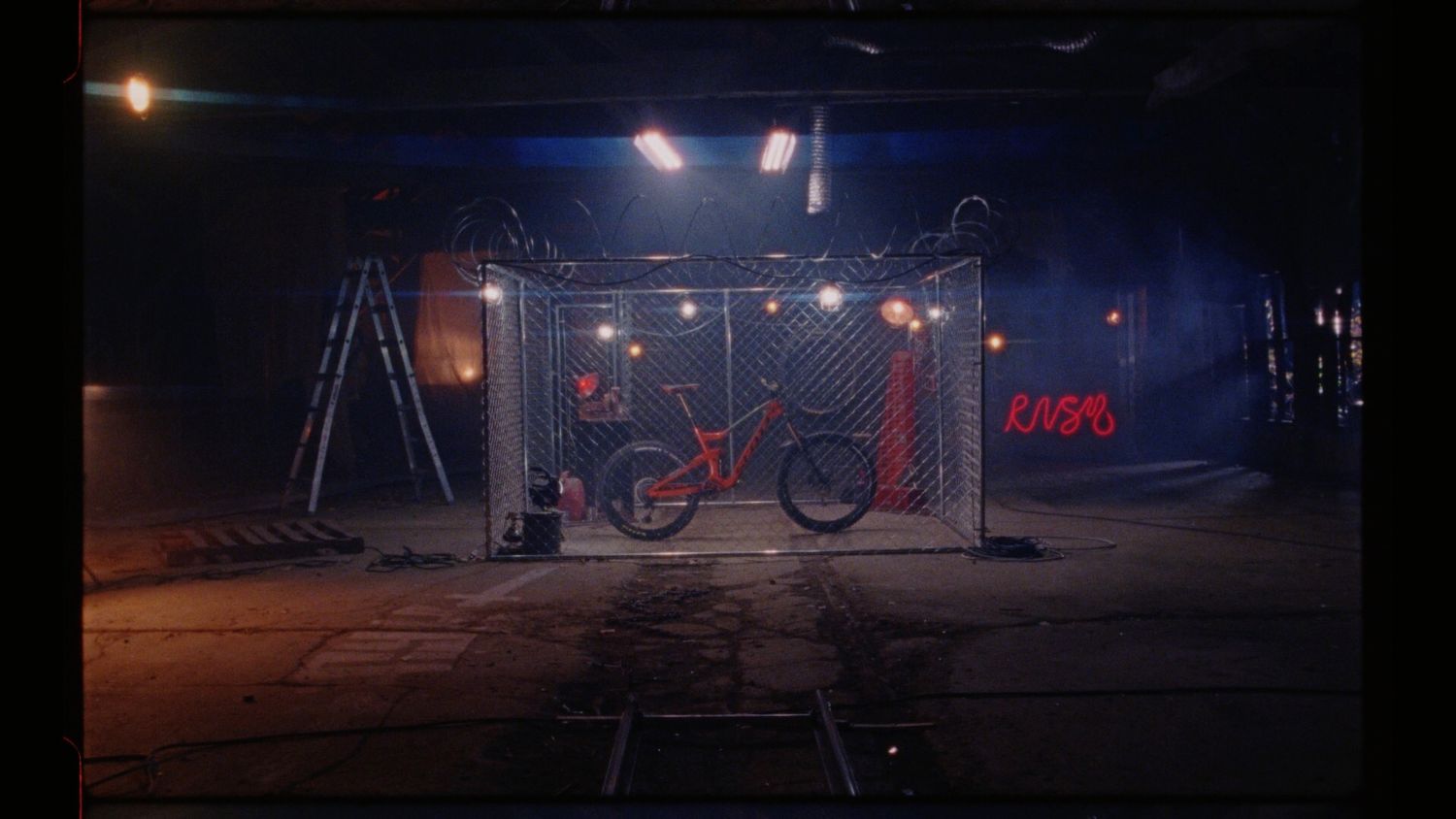 Mountain bike displayed under dramatic stage lighting in dark industrial setting.
