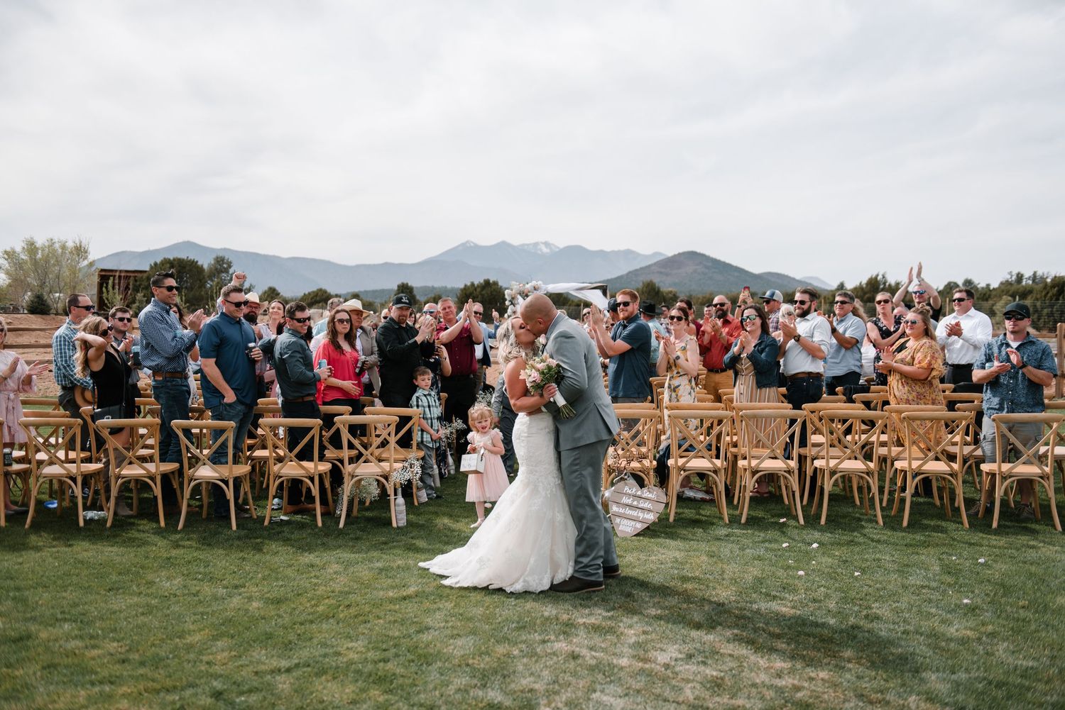 Outdoor wedding ceremony setup with wooden chairs and mountain views in the background.