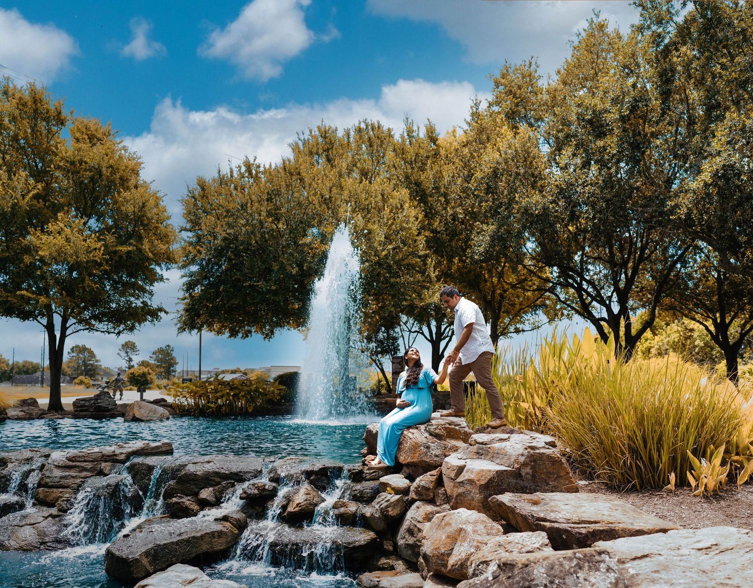 A romantic photoshoot by a decorative water fountain surrounded by trees and rocks.