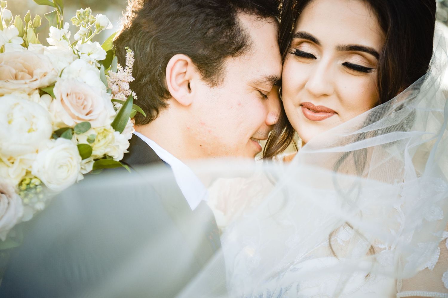 Romantic wedding portrait with soft white flowers and delicate veil.