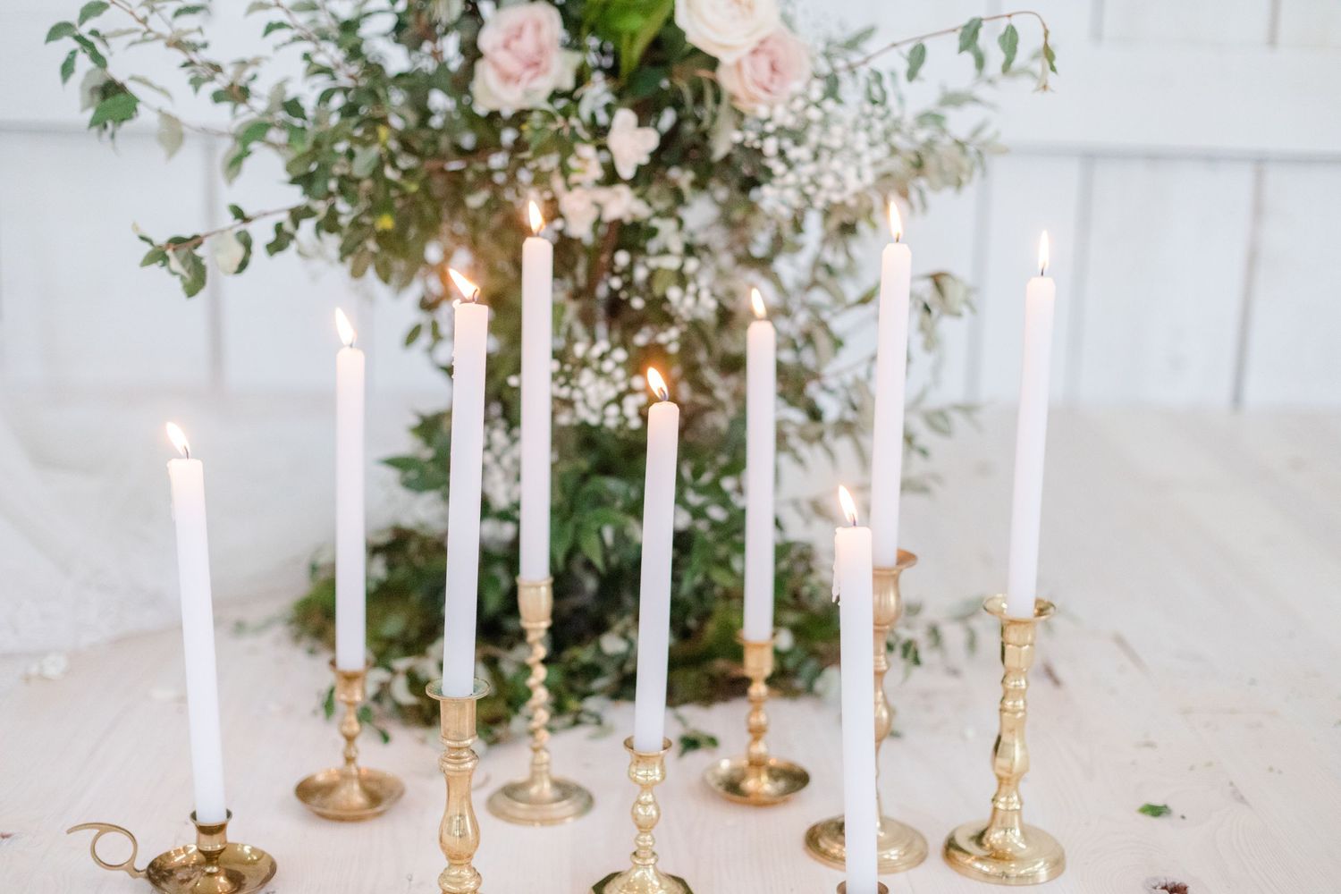 Elegant wedding table setting with white candles and floral arrangements.