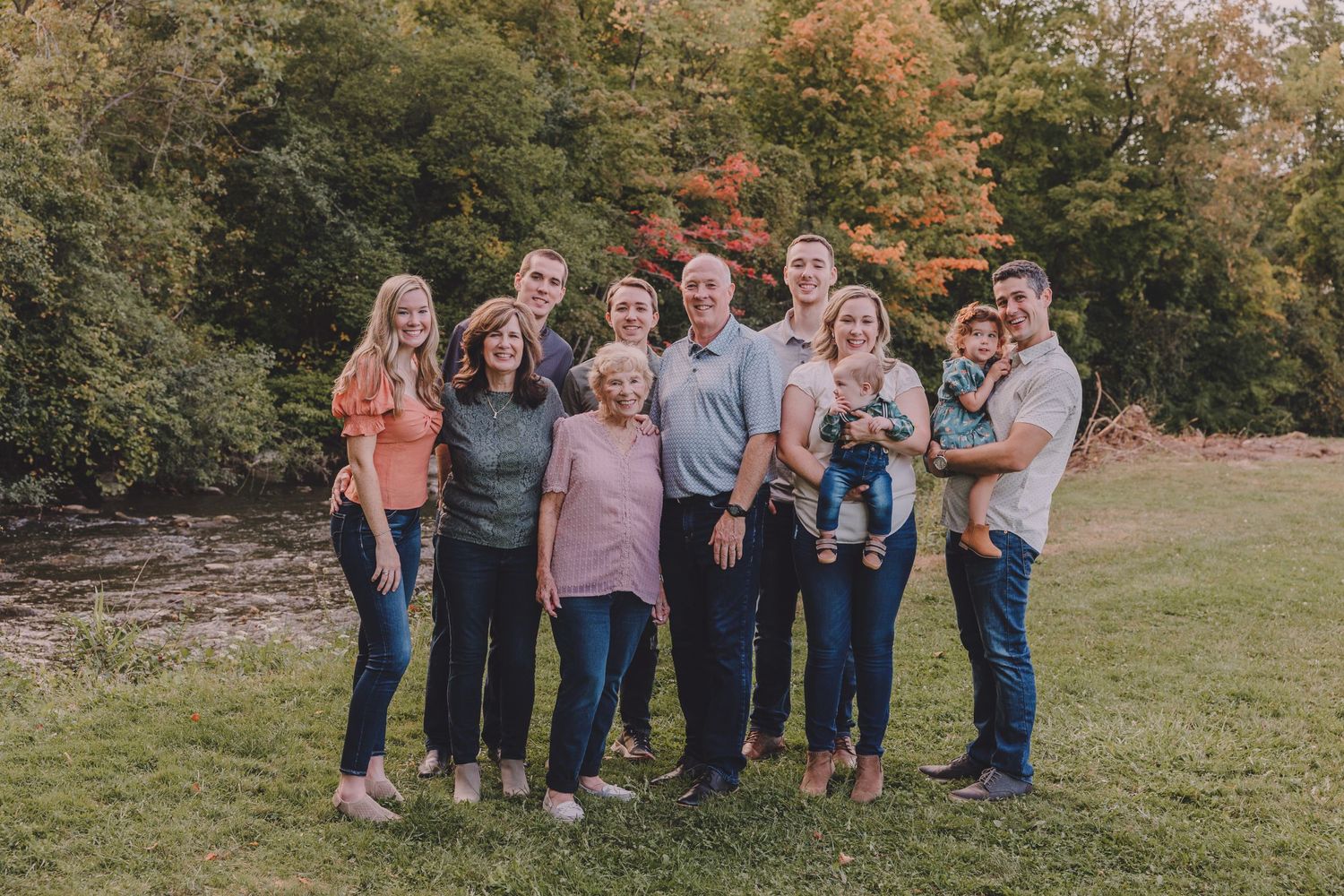 Multi-generational family photo with everyone gathered close together outdoors.
