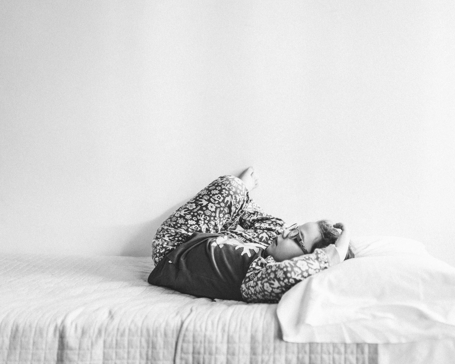 black and white lifestyle image of little girl lying in bed by Ella DM Photographer
