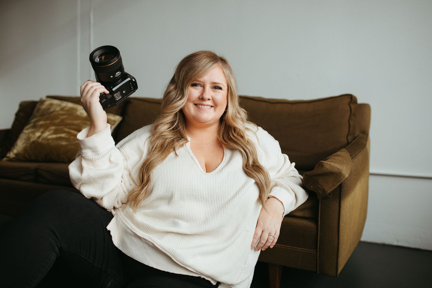 Relaxed portrait session on leather couch in bright minimal studio space.