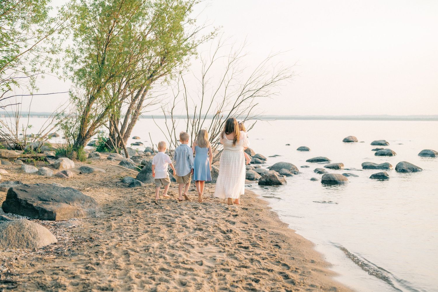 A serene beach scene with family members walking along the shoreline at sunset.
