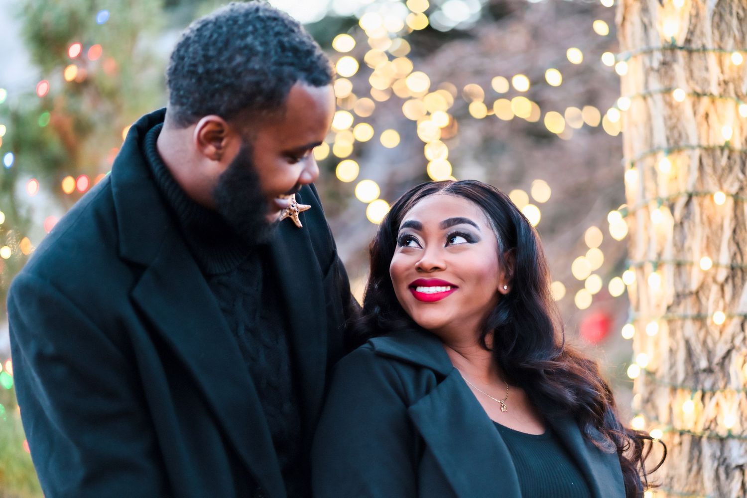 Couple shares an intimate moment outdoors with sparkling lights creating a romantic atmosphere.