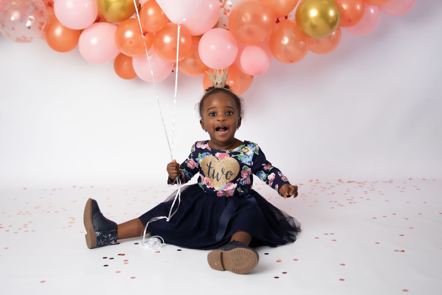 A joyful celebration with pink and gold balloons creates a festive photo backdrop.