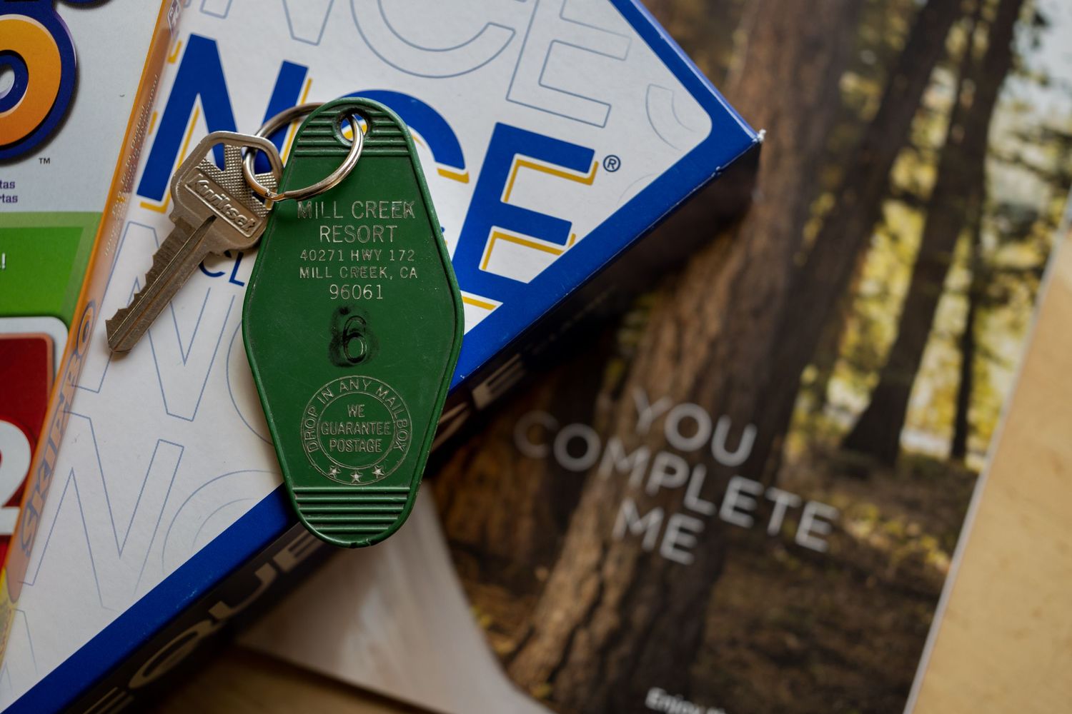 Vintage-style hotel key with green tag displayed against board game pieces.