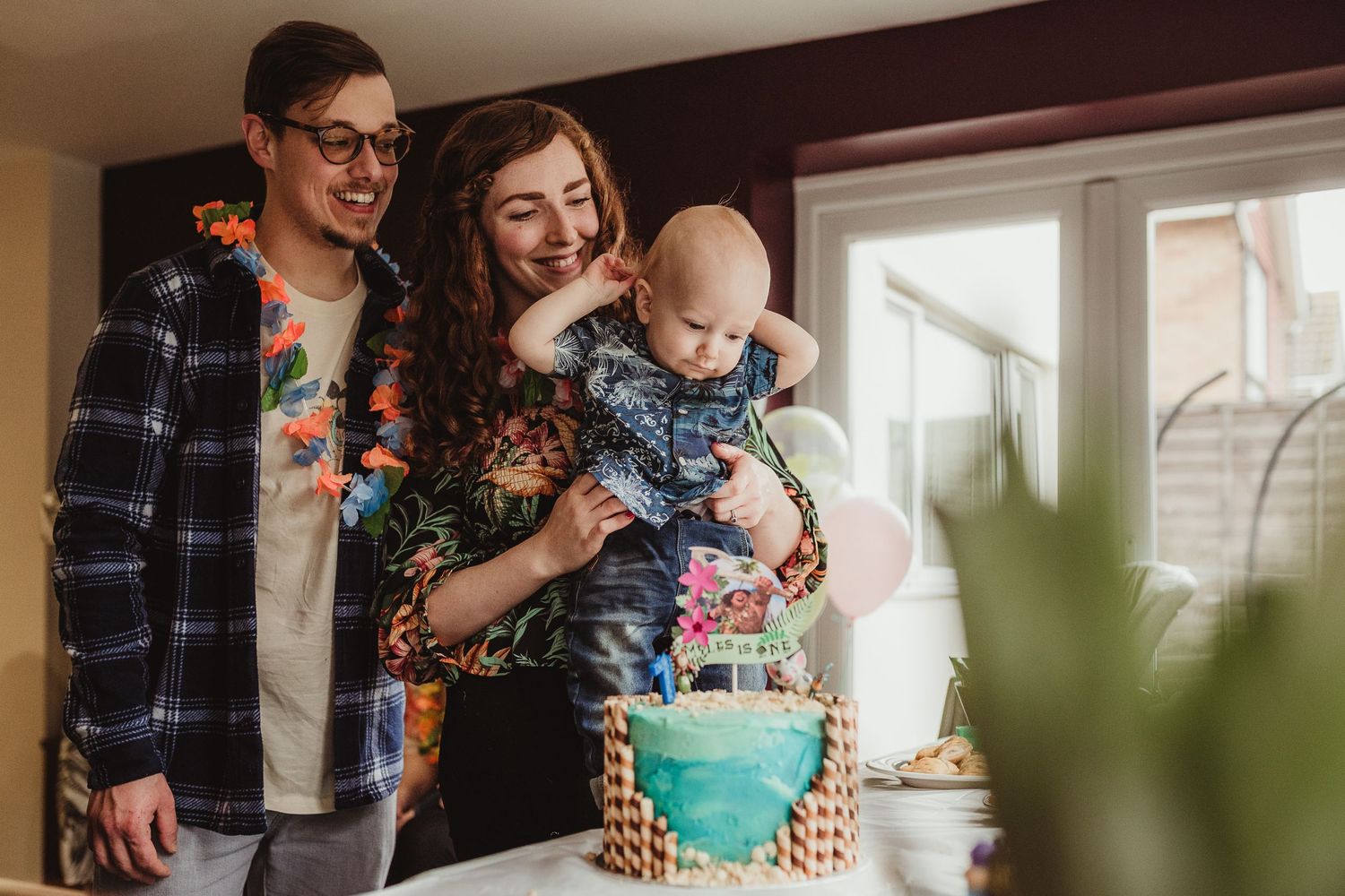 proud parents holding their one-year-old boy in front of his birthday cake family photographer hertfordshire