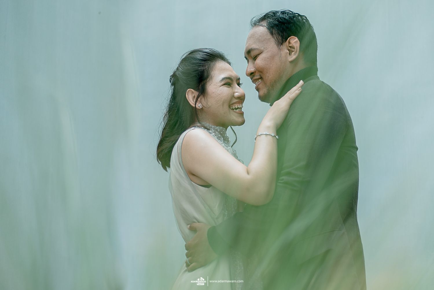 Romantic pre-wedding portrait in soft muted tones against misty background.