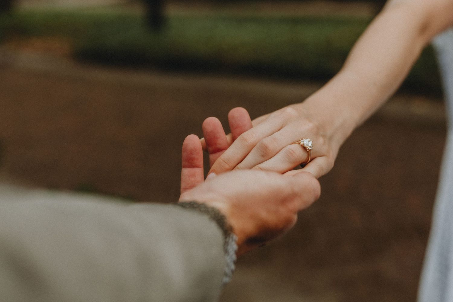 Two hands reaching together with one of them wearing an engagement ring