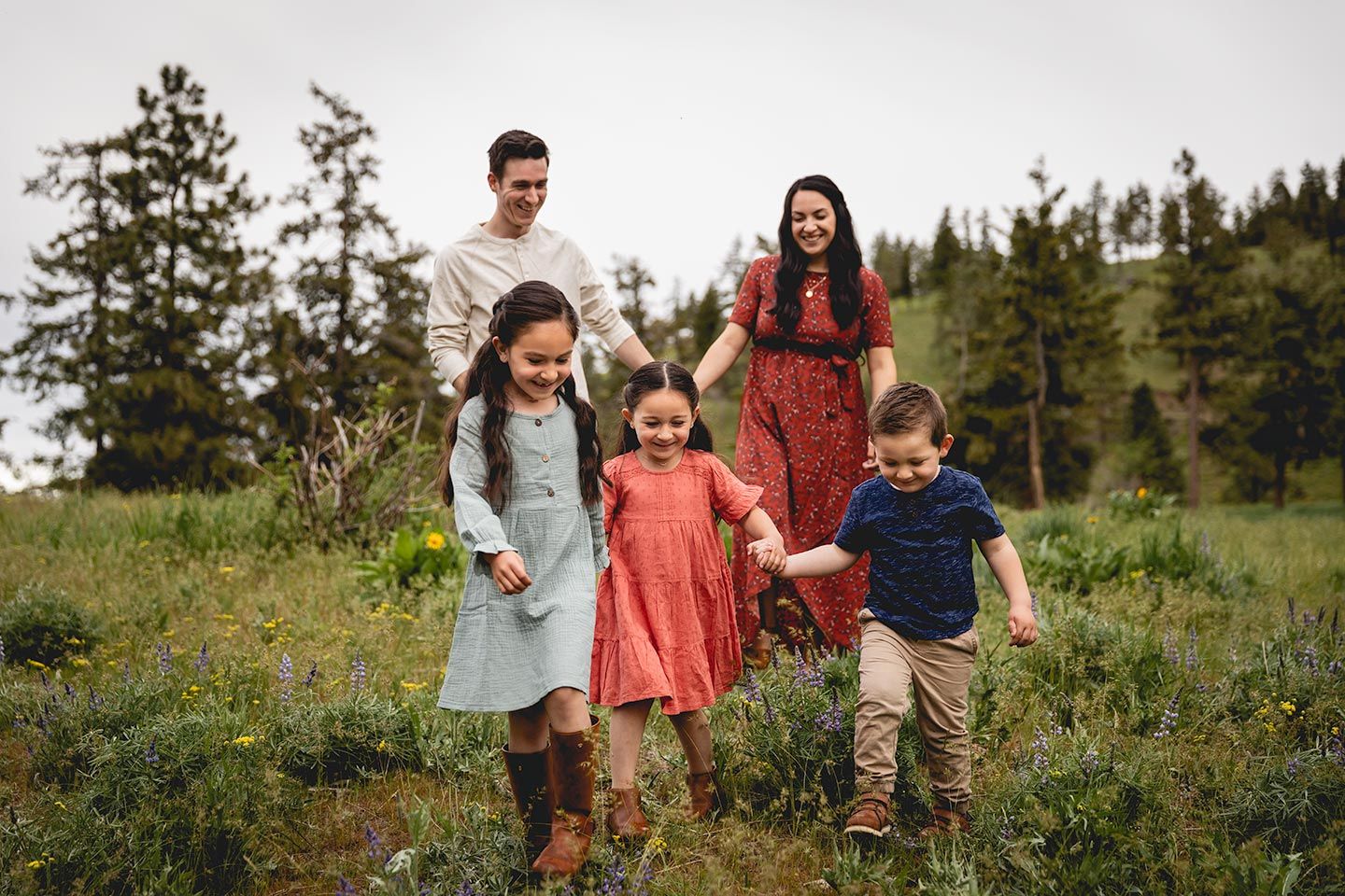 family holding hands and walking in mountain wildflowers near ellensburg, wa