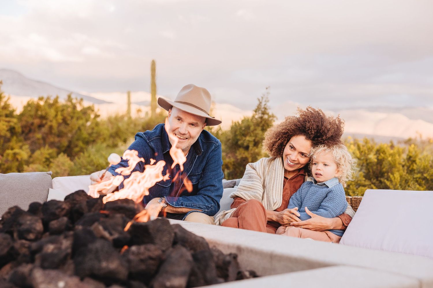Family enjoying time together by outdoor fire pit in desert setting.