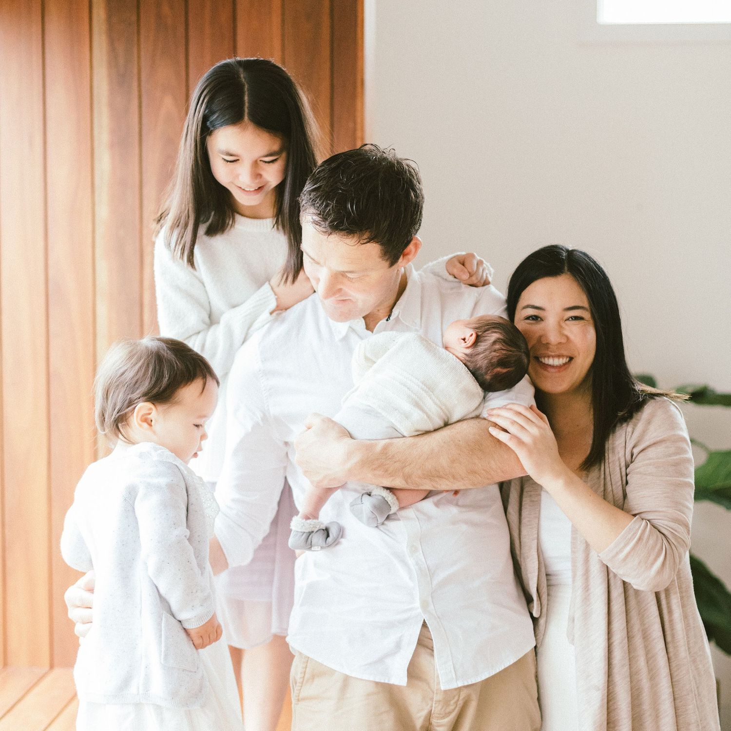 Light-filled indoor family portrait showing casual interaction and affection.