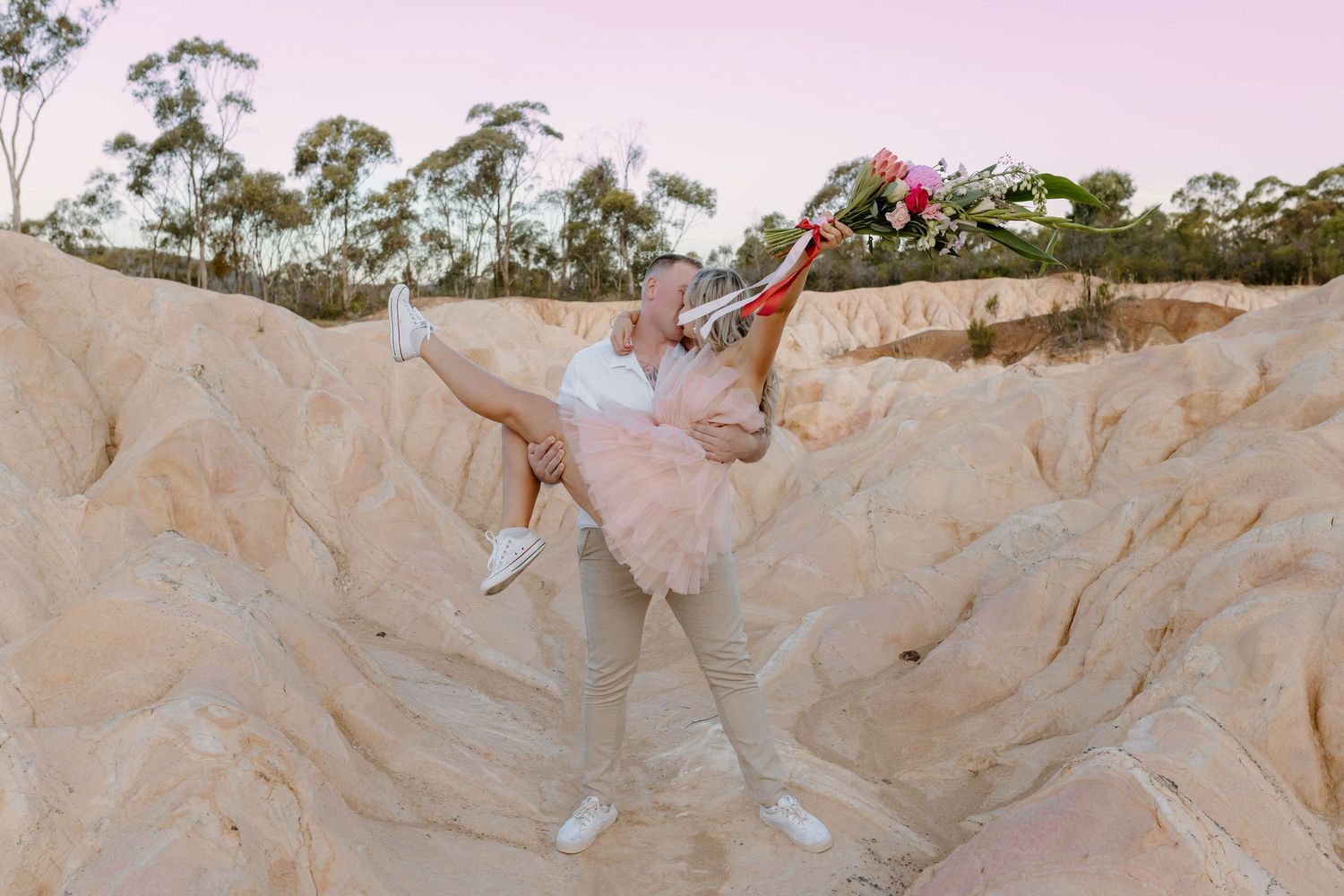 Person leaping energetically between beige rock formations in natural setting.