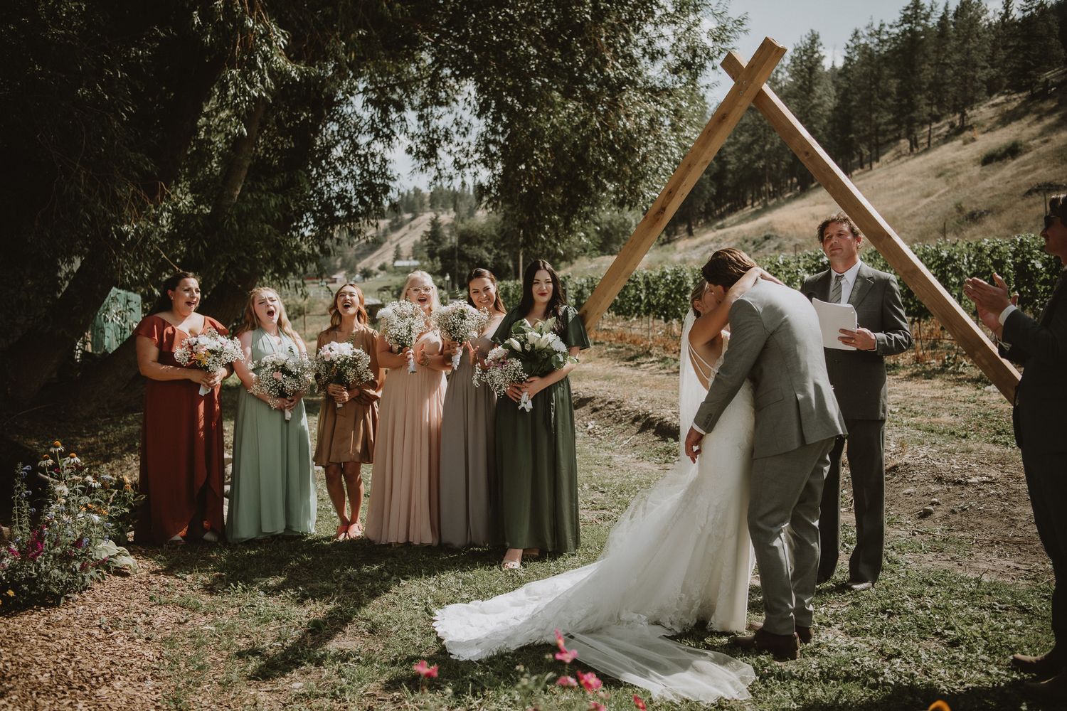 Bride and groom kiss at the altering during ceremony. Wedding in vineyard in Okanagan