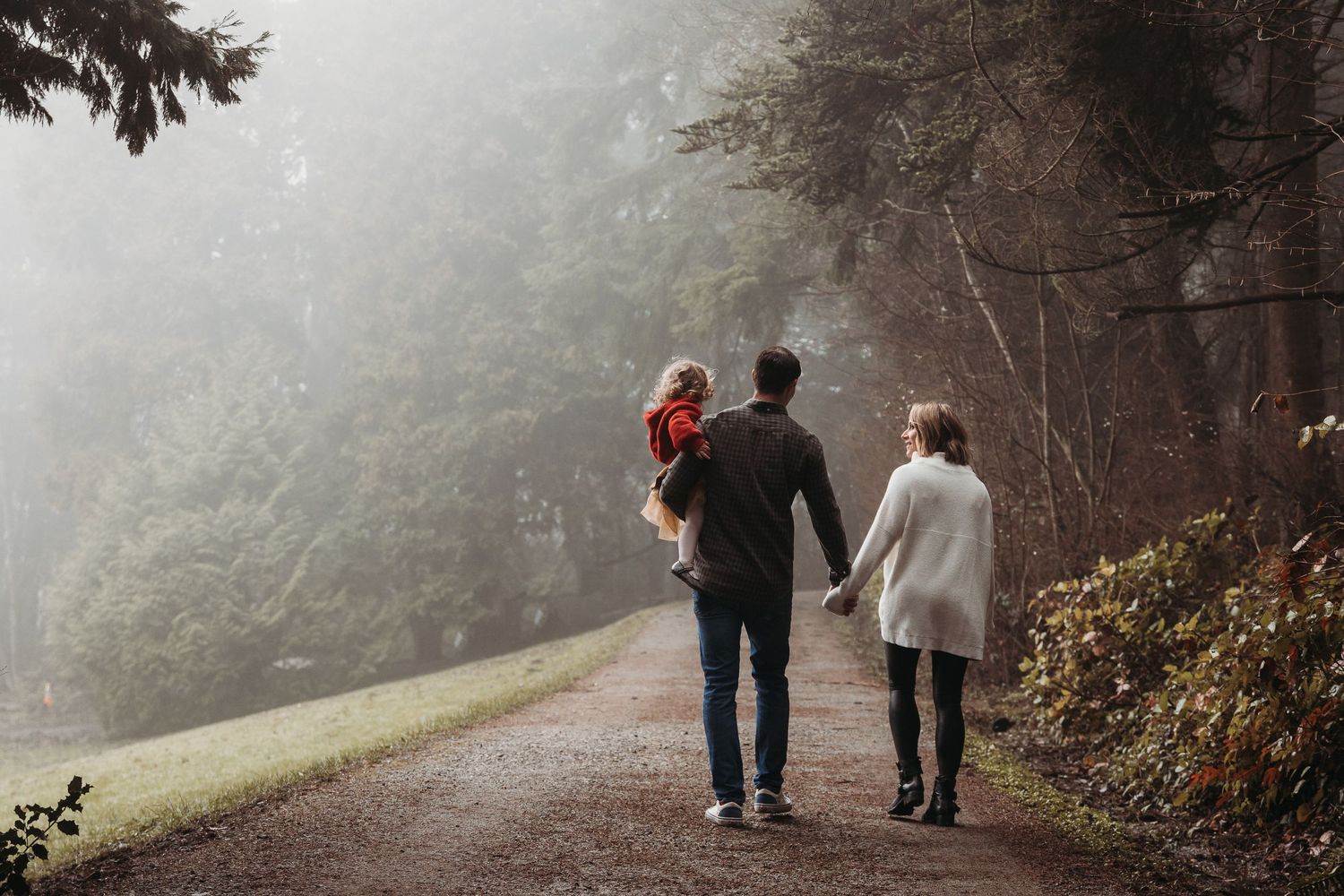 Misty forest pathway with silhouettes walking on a foggy autumn morning.