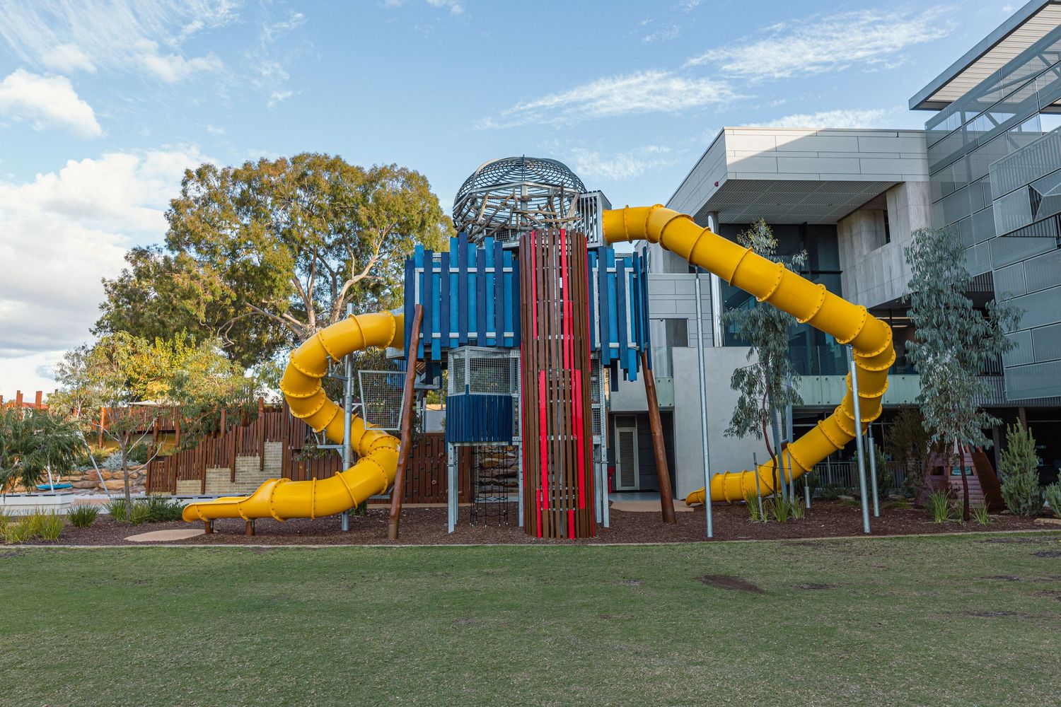 Large yellow spiral slide playground structure attached to blue and white building exterior.