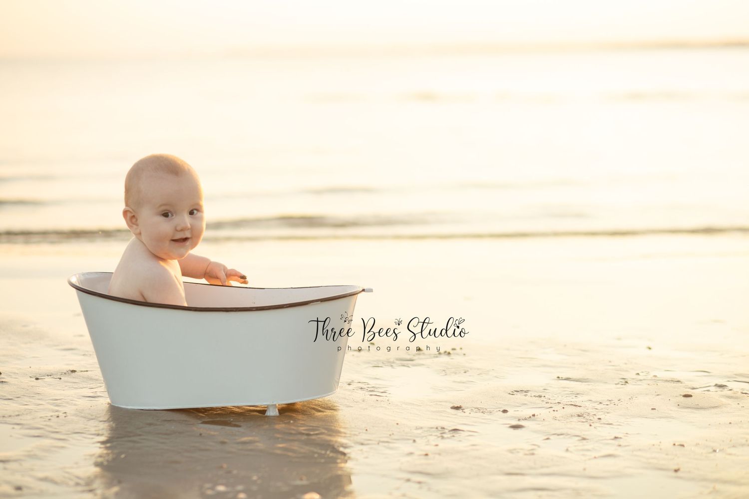 Vintage white bathtub on beach at sunset with soft golden lighting.