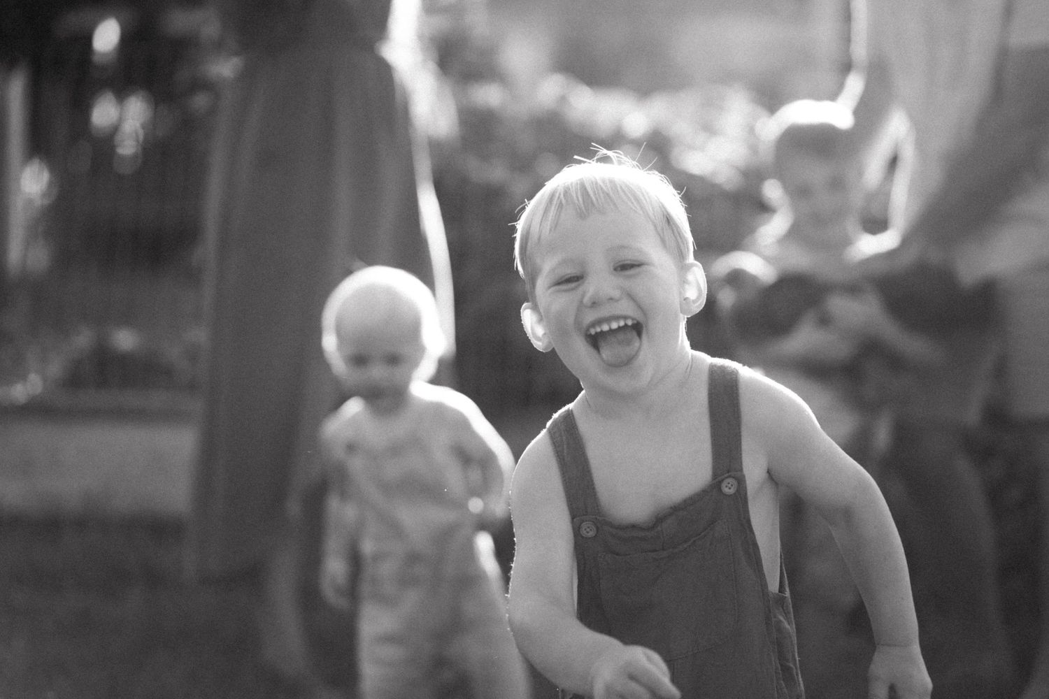 Black and white portrait of joyful young child laughing outdoors.