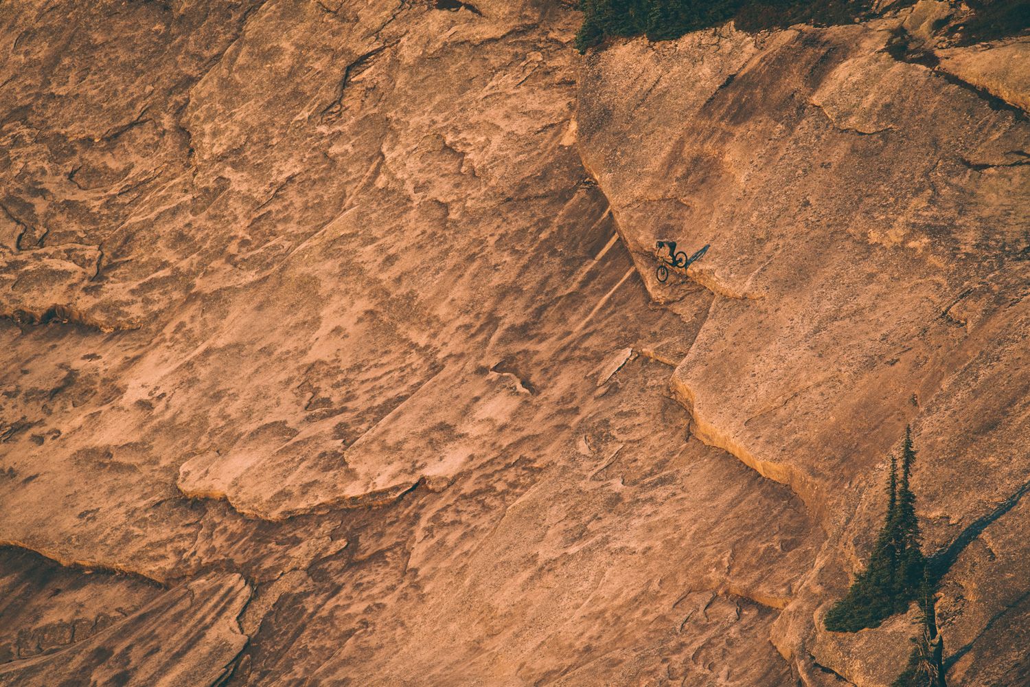 Close-up texture of weathered orange rock face with natural patterns and shadows.