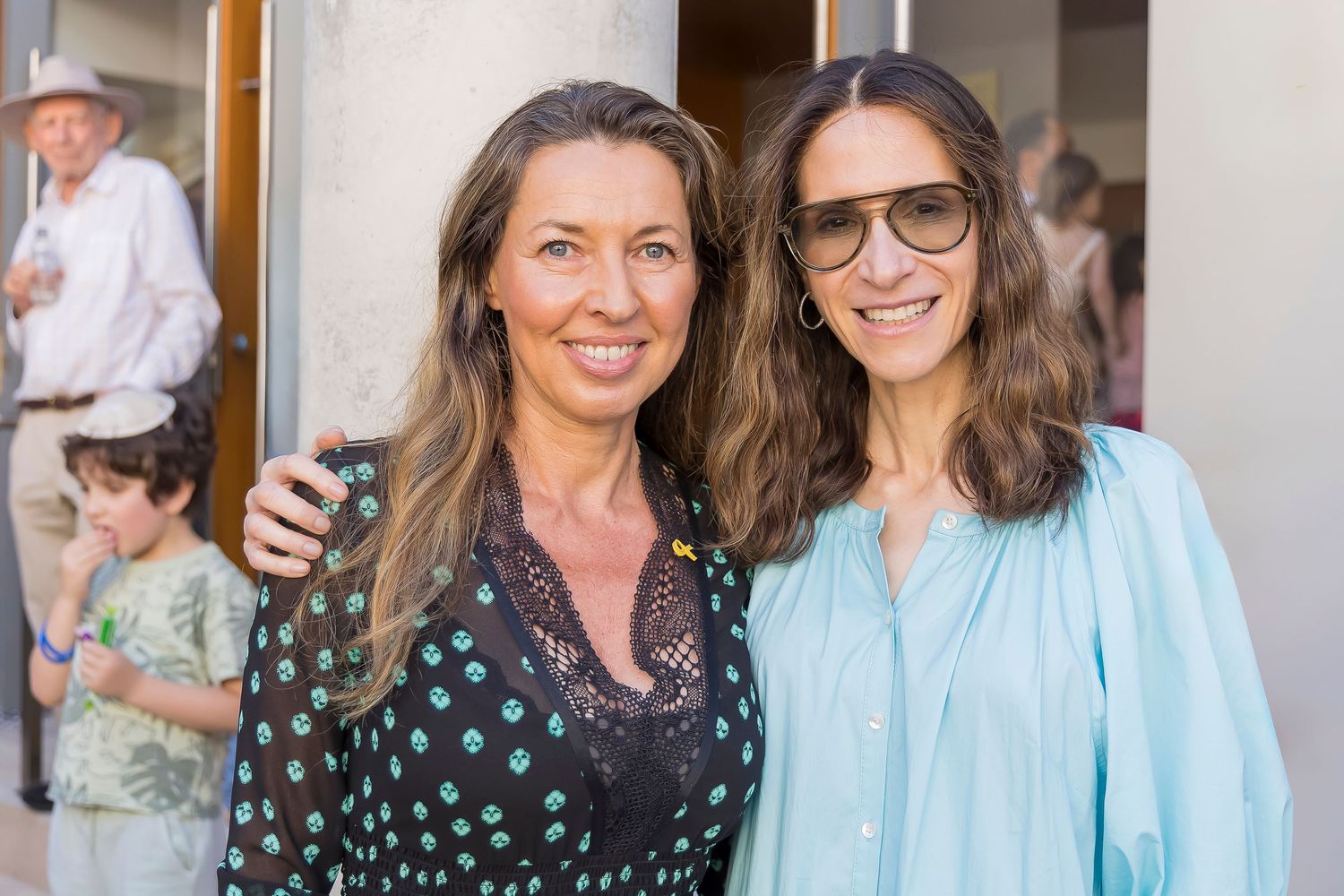 Two women smiling together at an outdoor event.